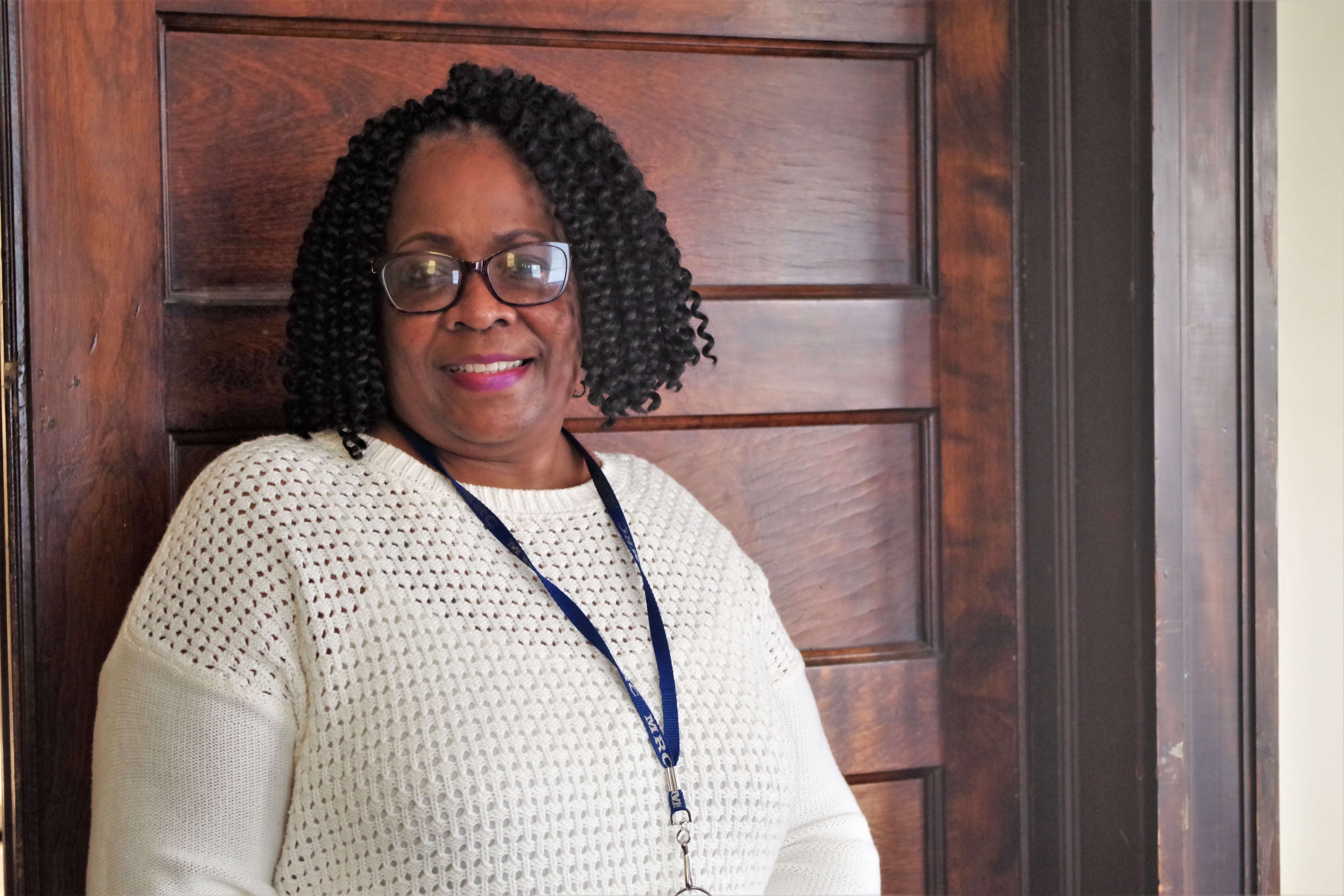 A woman standing in front of a wooden wall.