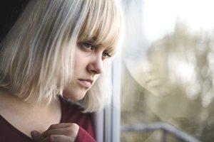 A teen girl looks out the window thinking about her past teen drug abuse