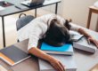 A woman sleeping on top of books in an office.