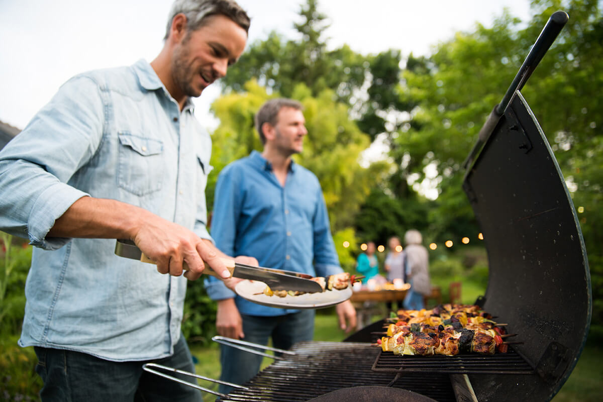 A group of men standing around a grill.