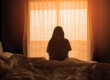 A person sitting on the bed looking out of a window
