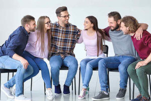 a group of people hugs and sits in chairs in an outpatient rehab